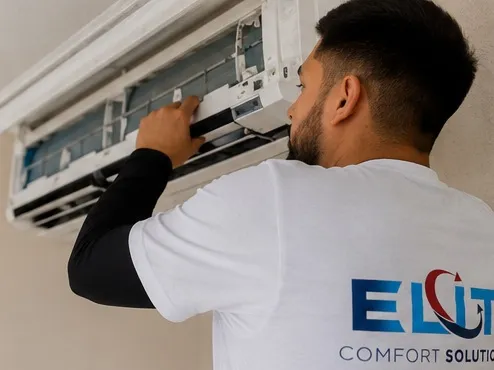 Elite Comfort Solutions technician servicing a wall-mounted ductless mini-split head